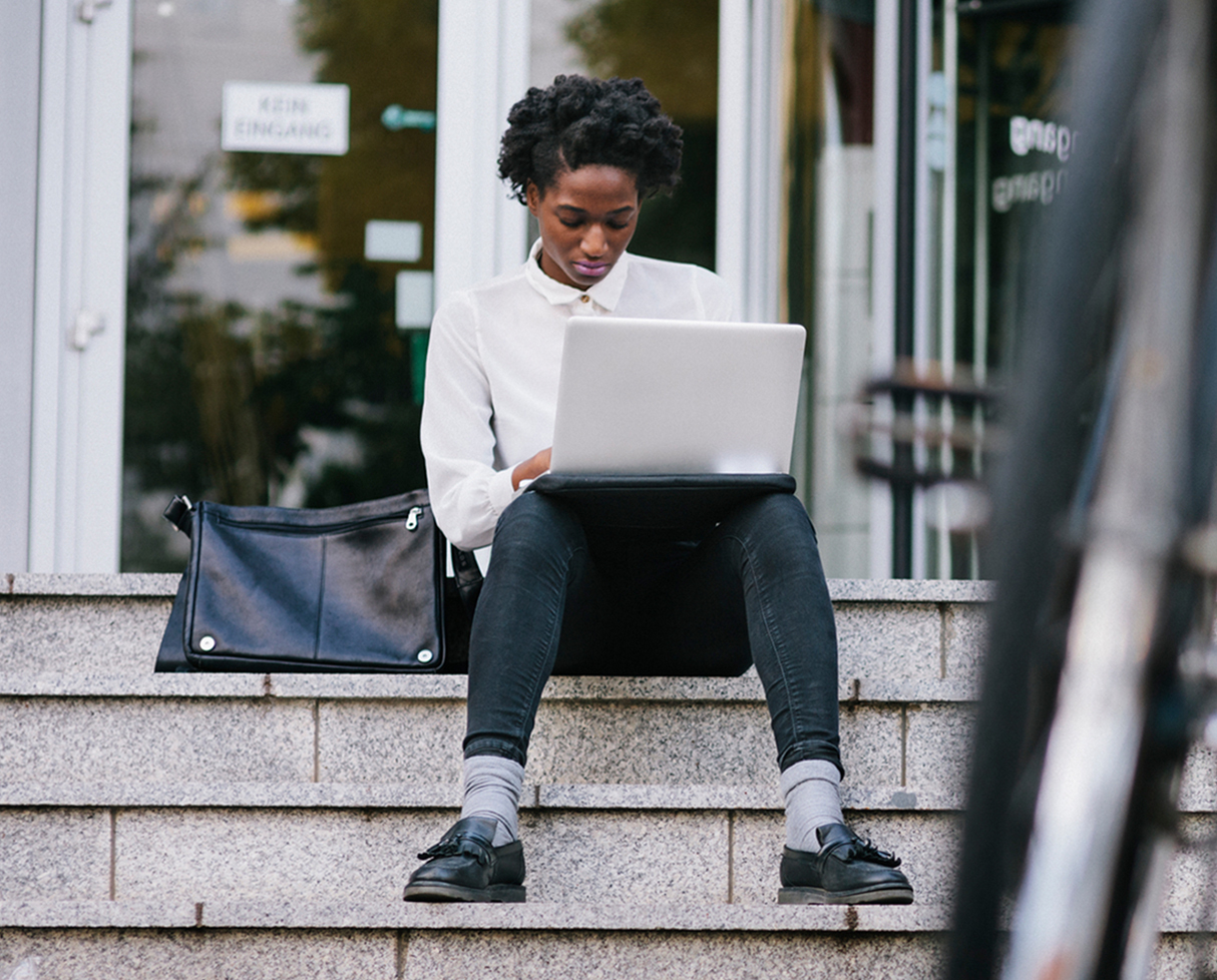 Student sitting on steps working on a laptop